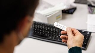 Kontrolle im Betrieb: Ein Mitarbeiter blickt in einem Produktionsgebäude einer bayerischen Bäckereikette auf das Ergebnis für einen Corona-Schnelltest eines Kollegen.