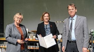 Wissenschaftsministerin Theresia Bauer (l.) überreicht Johanna Stachel (M.) das Bundesverdienstkreuz. Dekan Jürgen Berges (r.) gratuliert.