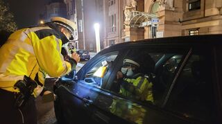 „Haben Sie einen Impfnachweis?“: Eine Autofahrerin streckt einem Beamten bei der Kontrolle in derAugustaanlage den gelben Impfpass entgegen.