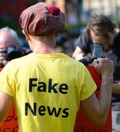Ein „Querdenker“ steht mit einem T-Shirt mit der Aufschrift „Fake News“ bei einer Kundgebung. (Symbolbild)