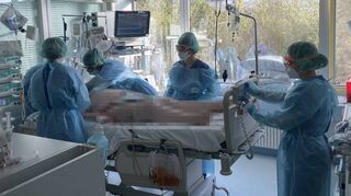 Kraftakt auf der Intensivstation: In zusätzlichen Anzügen, Hauben und Schutzbrillen kümmern sich fünf Pflegerinnen darum, dass eine narkotisierte Patientin vom Bauch auf den Rücken gedreht wird.