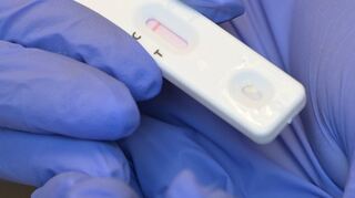 Eine Person hält während eines Corona-Tests den Plastikstreifen mit dem negativen Testergebnis in der Hand.