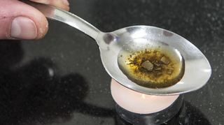 Ein Mann „kocht“ sich auf einem Löffel die Dosis für einen Schuss Heroin. (Symbolbild)