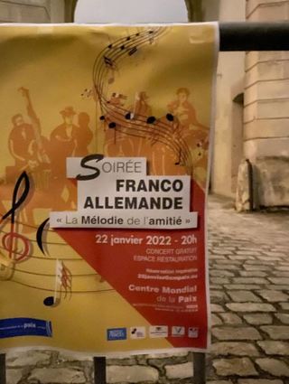 Ein Plakat am Weltzentrum für Frieden, Freiheit und Menschenrechte verweist auf den „Französisch-Deutschen Abend – Die Melodie der Freundschaft.