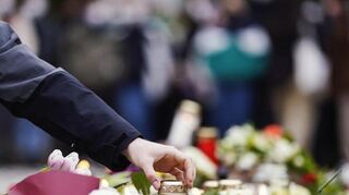 Menschen haben vor einem Gebäude der Heidelberger Universität Blumen und Kerzen niederlegt. Foto: Uwe Anspach/dpa