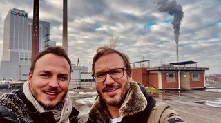 Die Atalanta-Geschäftsführer Jonas (links) und Jan Machuletz auf dem Dach des ehemaligen Isodraht-Verwaltungsgebäudes an der Rhenaniastraße. Im Hintergrund ist das Grosskraftwerk Mannheim (GKM) zu sehen.