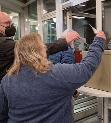 Teilnehmer werfen ihre Umfragezettel in die Box.