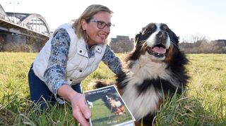 Elke Wiggert mit ihrem neuen Buch und Hündin Lucy auf der Ilvesheimer Neckarwiese.