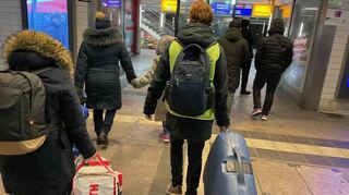Ein Ehrenamtlicher der Bahnhofshelfer (gelbes Leibchen) begleitet eine ukrainische Frau mit ihren zwei Kindern (im Bild links).