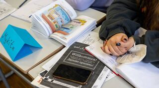 Ein Mädchen aus der Ukraine sitzt mit ihrem Unterrichtsmaterial in einer Willkommensklasse eines Gymnasiums.