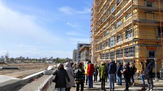 Besucherinnen und Besucher des Baustellenfestes an der Promenade des Wohngebiets, die einen Ausblick auf das Buga-Gelände bietet.