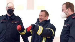 Die Feuerwehr überreicht ihrem neuen Chef eine Einsatzjacke.