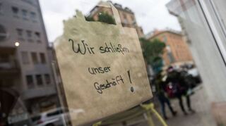 Eine Papiertasche mit der Aufschrift „Wir schließen unser Geschäft“ hängt an einem Einzelhandelsgeschäft in der Innenstadt.
