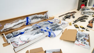 Beweismittel in Form von Waffen, die bei einem SEK-Einsatz in Boxberg sichergestellt wurden, liegen eingepackt in Plastikfolie auf einem Tisch im Polizeipräsidium Heilbronn. Zur Veranschaulichung liegen daneben typgleiche Waffen.