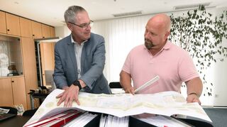 Bürgermeister Andreas Metz (l.) und Bauamtsleiter Pascal Tholé mit den Plänen für das Kombibad. In den Ordnern sind die Genehmigungsunterlagen.