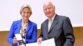 Wirtschaftsministerin Nicole Hoffmeister-Kraut überreicht das Verdienstkreuz 1. Klasse an Manfred Fuchs in der Aula der Universität.