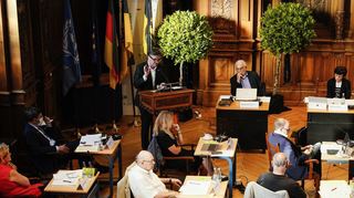 Manfred Lucha (l. hinten) gibt dem Heidelberger Gemeinderat sein Ehrenwort. Der bleibt unbeeindruckt.