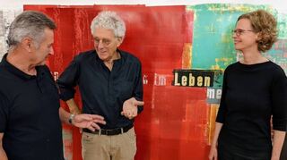 Der Künstler Rainer Negrelli (M.) vor einer Buchrolle mit Rilke-Vers im Gespräch mit Bernd Gerstner (Kunstverein) und Laudatorin Kim Behm.