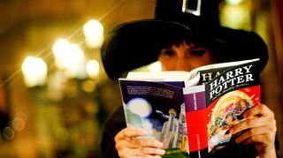 Ein Fan mit Zauberhut schmökert in einem Harry Potter-Band – auch Erwachsene entdeckten Freude an der fantastischen Jugendbuch-Reihe.