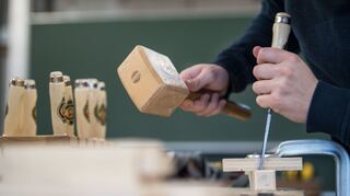 Ein Auszubildender im Handwerk arbeitet am an einer Berufsschule in Ludwigsburg (Baden-Württemberg) an einer Werkbank mit Holz.