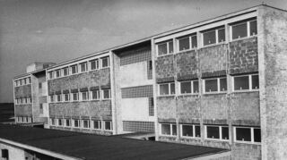 Das Gymnasium nutzte Räume der ehemaligen Petersen-Hauptschule (oben, im Jahr 1960), das Bild unten zeigt einen Teil der Gebäude im Jahr 1977.