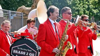 Die Männer mit den roten Anzügen der mobilen Brass-Band „Brass2Go“ sorgen am Wasserturm für gute Stimmung.
