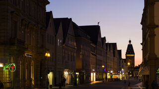 Blick im Sonnenuntergang bei dunkelblauem Abendhimmel in die bereits von Straßenlaternen beleuchtete Maximilianstraße in Speyer. Hinten das noch angestrahlte Altpörtel.
