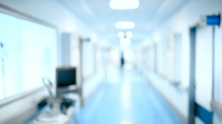 Blurred hospital hallway, unfocused background.