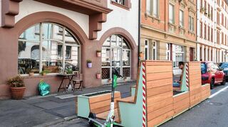 Sitzinseln aus Holz vorGründerzeit-Stadthäusern: Aus Holz gezimmert und bepflanzte „Parklets“ und andere Elemente sollen die Blumenstraße in der Heidelberger Weststadt „gemütlicher“ machen.