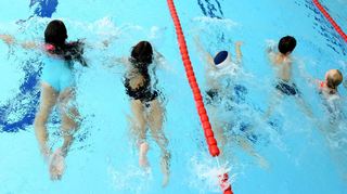 In der Schwimmhalle nehmen Schülerinnen und Schüler am Schwimmunterricht teil.
