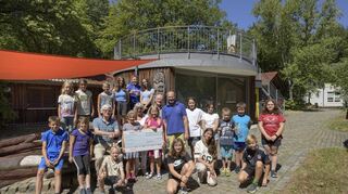 Christel Zachert (M.) übergibt mit Mann und Werner Tetsch (sitzend) einen Scheck über 120 000 Euro an den stellvertretenden Campleiter Florian Münster.
