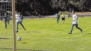 Torhüter, Abwehrspieler und Stürmer schauen dem Ball gespannt hinterher, der Schuss von Viernheims Kapitän Laurenz Baaß (Mitte, weißes Trikot) landet aber am Pfosten.