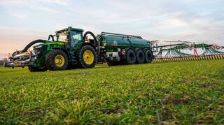 Ein Landwirt bringt mit seinem Gespann Gülle auf einem Feld aus.