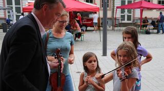 Musikschulleiter Rùnar Emilsson erklärt jungen Besucherinnen den Umgang mit Instrumenten wie Geige oder Trompete.