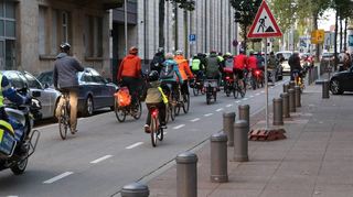 Die Critical Mass bewegt sich als Teil des Straßenverkehrs. Rechts im Bild blockiert ein Teilnehmer die Ausfahrt der Tiefgarage U 2, damit das Auto den Verband nicht auseinanderreißt.