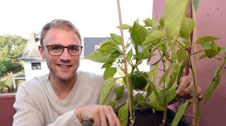 Florian König auf dem Balkon seiner Eigentumswohnung am Hochbeet mit Paprika und Peperoni.