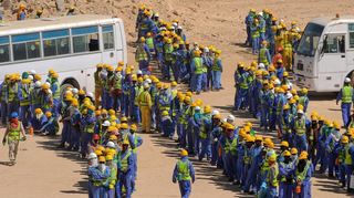 Bauarbeiter warten in Doha vor den Bussen auf die Rückfahrt in ihre Unterkünfte.