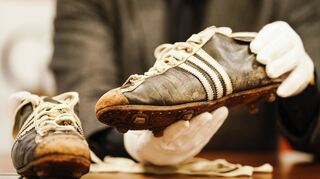 Ein Auktionator hält die Fußballschuhe der Weltmeisterschaft von 1954 des verstorbenen Fußballspielers Horst Eckel in den Händen.