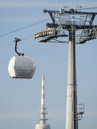 Eine Seilbahn-Kabine mit der Aufschrift ·BUGA· hängt vor dem Mannheimer Fernmeldeturm.