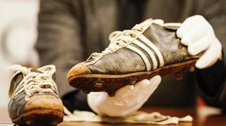 Ein Auktionator hält die Fußballschuhe der Weltmeisterschaft von 1954 des verstorbenen Fußballspielers Horst Eckel in den Händen.