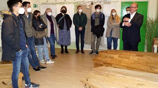 Alex Hahn (r.) erklärt den Mitgliedern der KHG (5.v.l.: Kathrin Grein), warum ein Sarg sauerstoffdurchlässig sein muss.