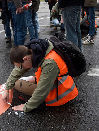 Ein Aktivist klebt seine Hand an der Bismarckstraße auf den Asphalt.