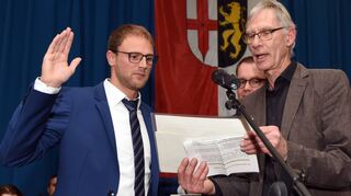 Bürgermeister Florian König (l.) wird von Walter Heilmann (r.) ins Amt eingeführt. Pfarrer Markus Miles (Mitte) hält die Bibel, auf der Königs Hand liegt.