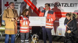 Thorsten Riehle (l.) übergibt vor dem neuen Einsatzleitwagen den Scheck der „Mannheimer Runde“ an die DRK-Rettungshundestaffel.