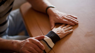 Ein Mann hält die Hand seiner Ehefrau, die an Alzheimer erkrankt ist.