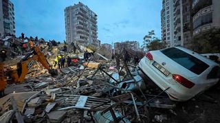 Notfallteams suchen nach Menschen in einem zerstörten Gebäude, während ein Auto auf den Trümmern liegt. Nach mehreren schweren Erdbeben in der türkisch-syrischen Grenzregion ist die Zahl der Toten auf mehr als 1900 gestiegen