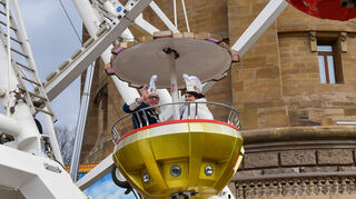Daniela II. und Ben I. grüßen aus der Gondel vom 35 Meter hohen Riesenrad am Wasserturm zum Abschluss vom kleinen Umzug der Fasnachter in Mannheim.