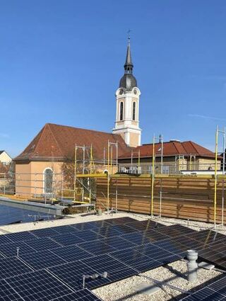 Die neue Solaranlage auf dem Dach, im Hintergrund die Kirche.