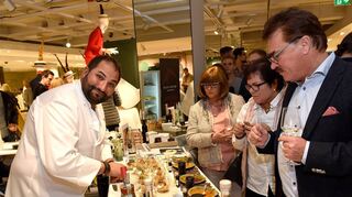 Eindrücke eines früheren Gourmetfestivals im Modehaus: Hier bereitet Metin Calis für die Gäste ein Gericht zu.
