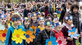 Die Kinder der Woogbachgrundschule haben selbst gebastelte Blüten umhängen, während sie beim Umzug mitlaufen.